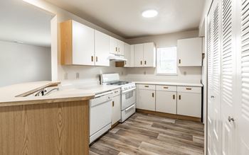 A kitchen with white appliances and wooden cabinets.